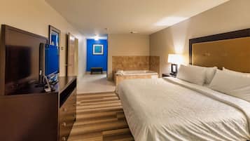 Una habitación de hotel con cama, televisión, baño con bañera y escritorio con computadora.