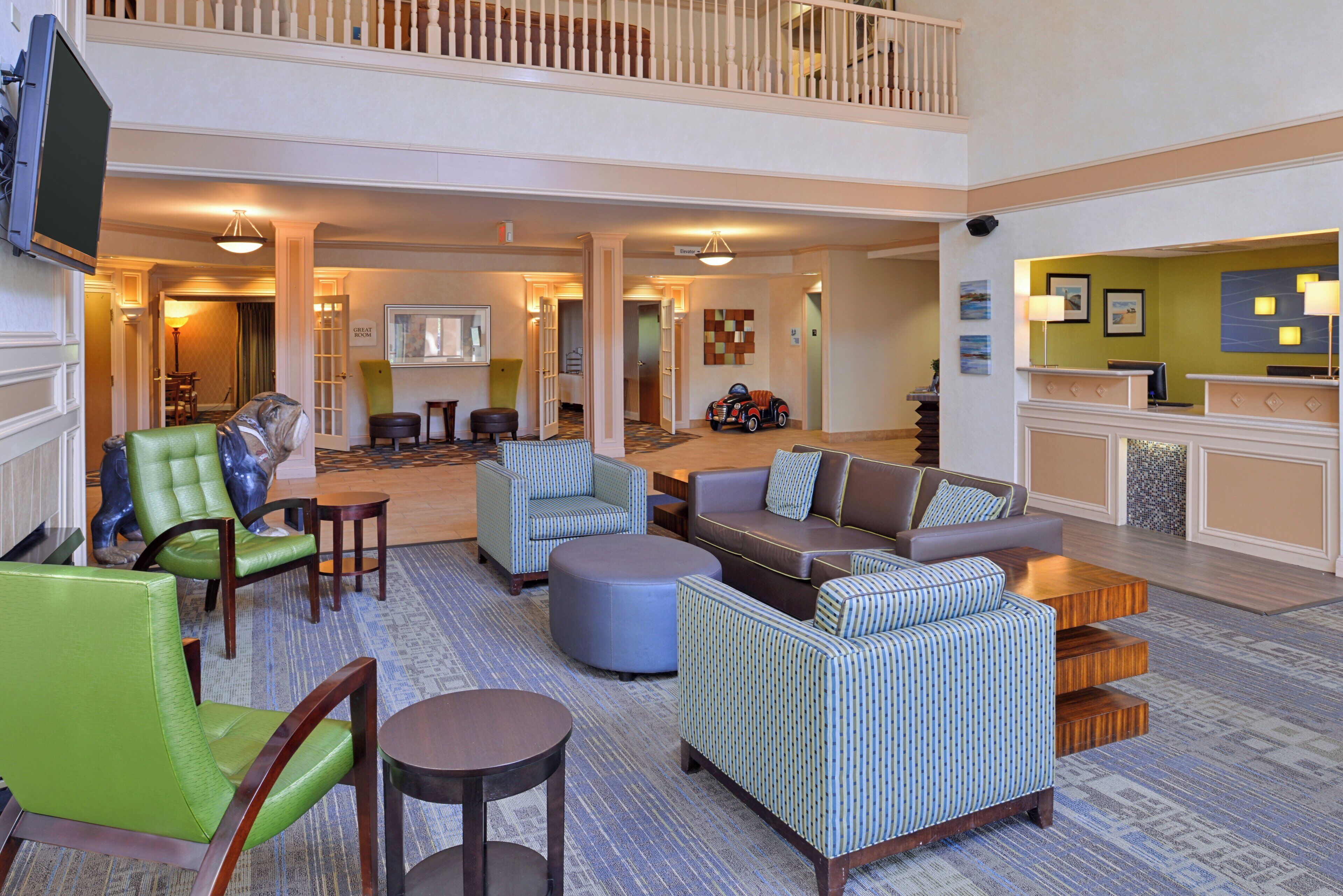A spacious lobby with multiple seating areas, a reception desk, and a staircase leading to an upper level.