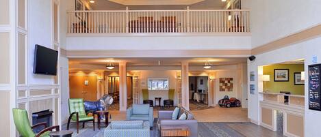 A spacious lobby with a high ceiling, a balcony, and a check-in counter.