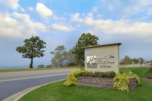 A sign for Holiday Inn Express & Suites with a view of the road and trees.