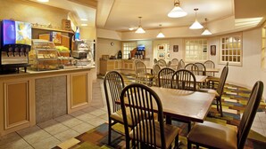 A restaurant with a central dining area, a counter with food items, and a bar area. - Holiday Inn Express & Suites St Joseph by IHG (Saint Joseph)