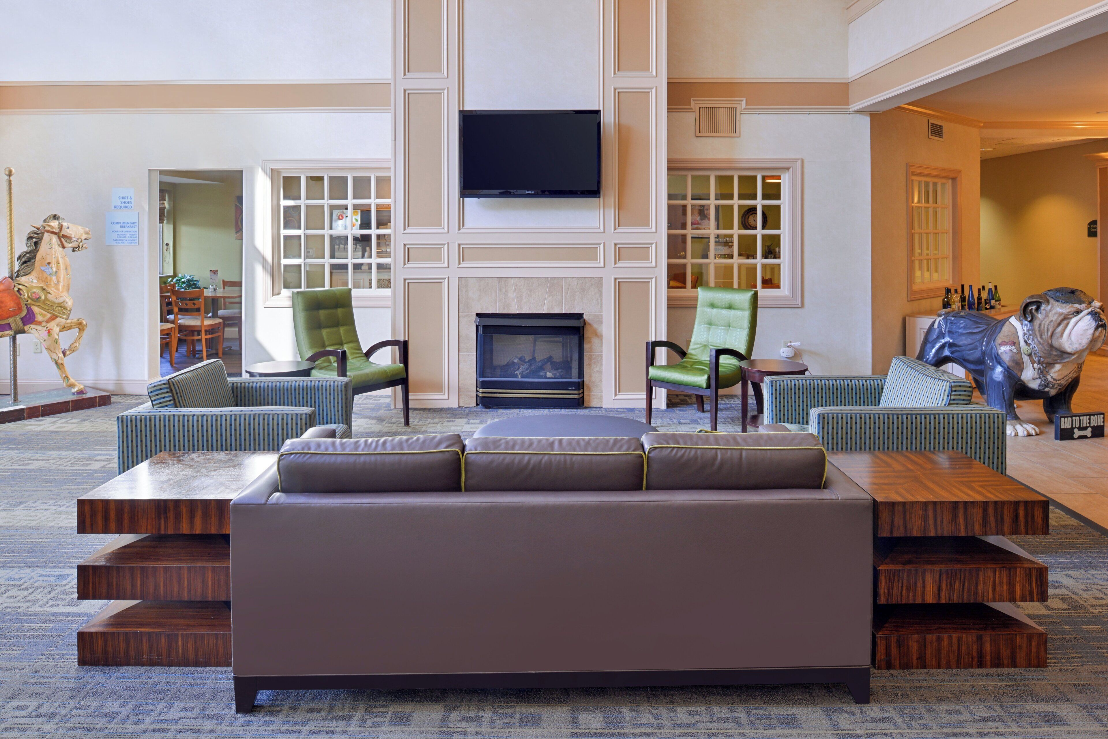A spacious lobby with a large seating area, a fireplace, and a television mounted on the wall.