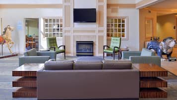 A spacious lobby with a large seating area, a fireplace, and a television mounted on the wall.