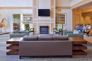 A spacious lobby with a large seating area, a fireplace, and a television mounted on the wall.