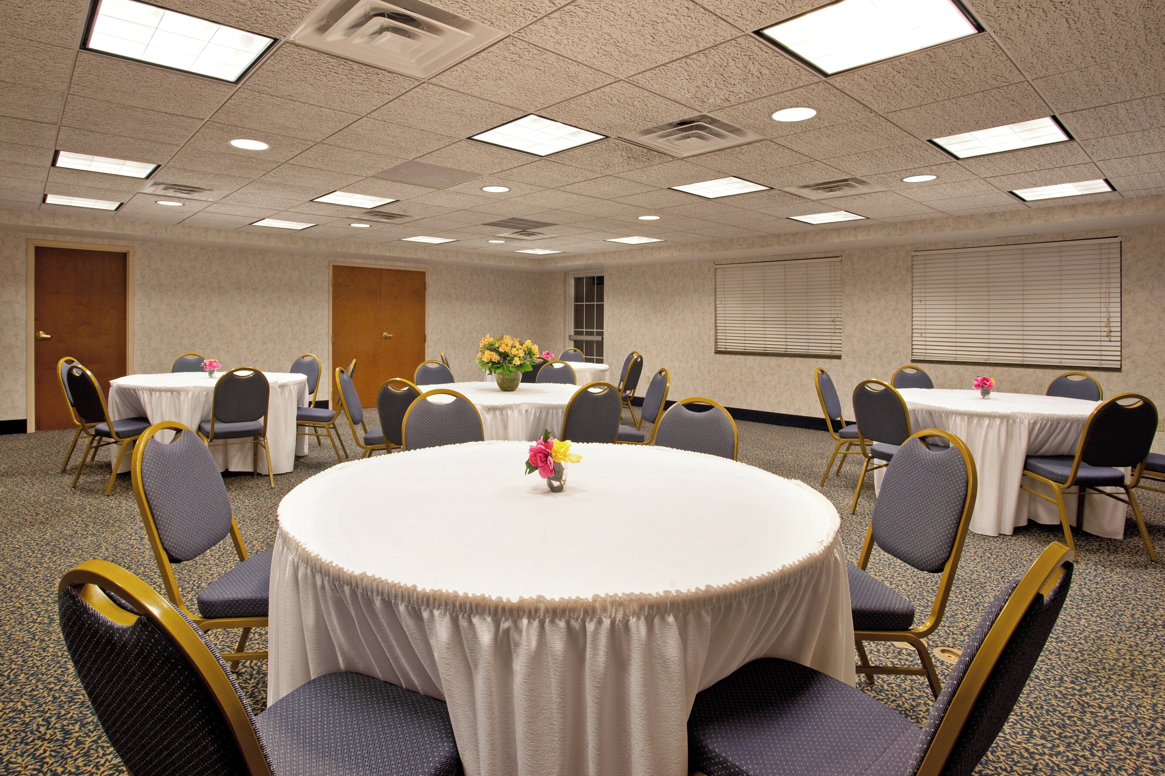 A conference room with round tables, chairs, and floral centerpieces.