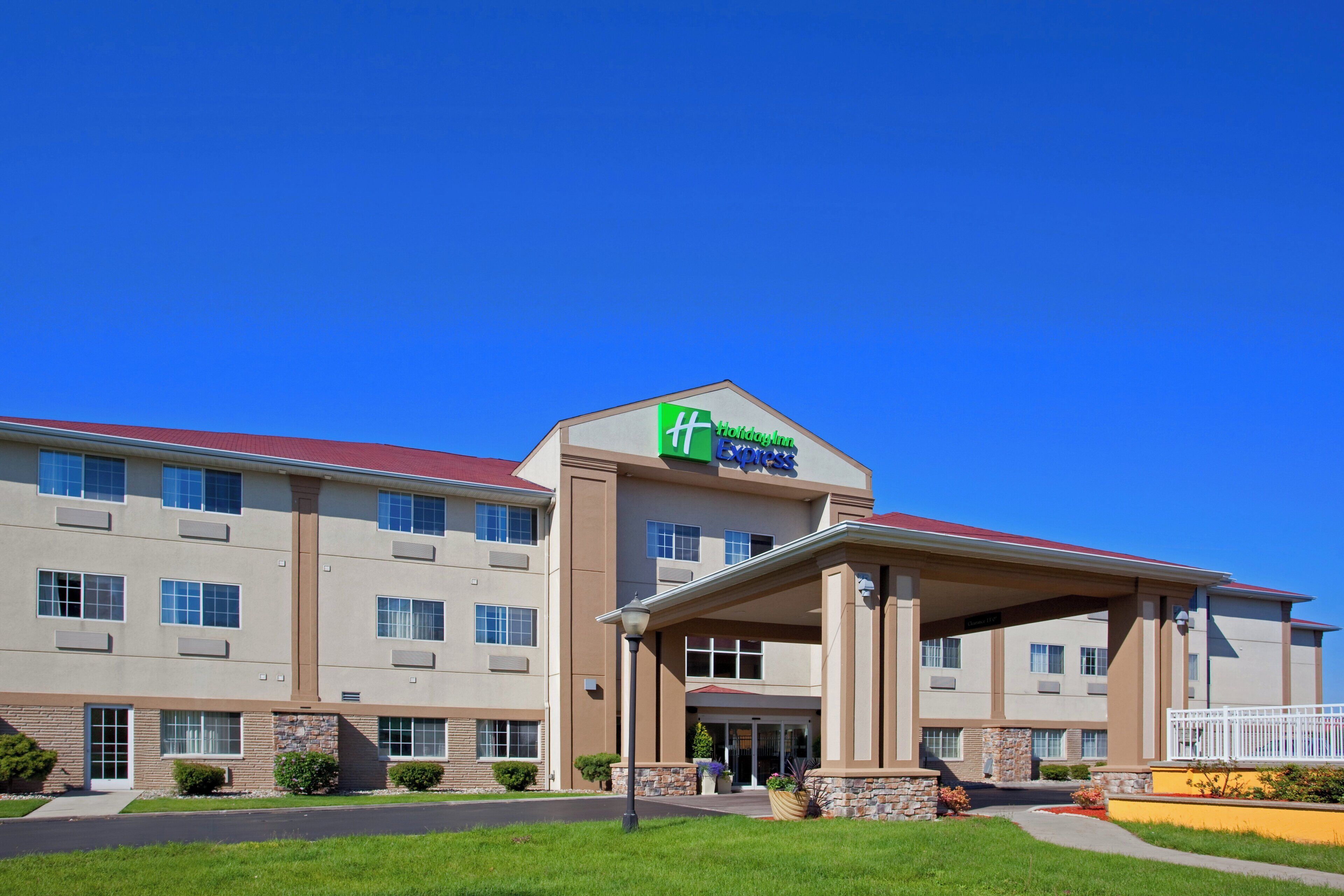 Ein Holiday Inn Express Hotel mit überdachter Eingangspartie, mehreren Fenstern und einem roten Dach.