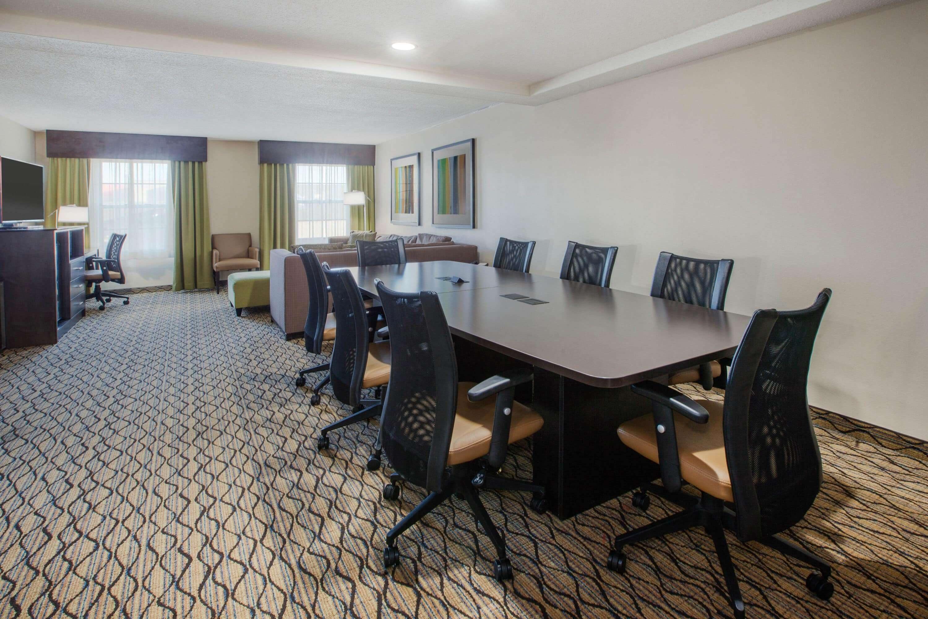 A conference room with a large table, several chairs, a sofa, and a TV.