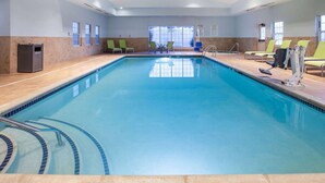 A swimming pool with a tiled edge, a lifeguard chair, and a window with blinds. - Wingate by Wyndham Roseville/Detroit (Roseville)