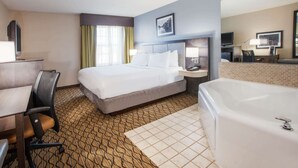 A hotel room with a bed, a desk, a chair, a desk lamp, a TV, a bathroom with a bathtub, and a window with curtains. - Wingate by Wyndham Roseville/Detroit (Roseville)
