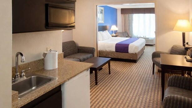 A hotel room with a kitchenette, a bed, a seating area, and a view of the outside. - Sleep Inn & Suites Kalamazoo East (Kalamazoo)