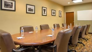 A conference room with a large wooden table, brown leather chairs, water bottles, and framed pictures on the wall. - Sleep Inn & Suites Kalamazoo East (Kalamazoo)