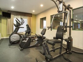 Un gimnasio con equipo cardiovascular, máquinas de pesas y un espejo.