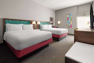 A hotel room with two beds, a desk, and a TV.