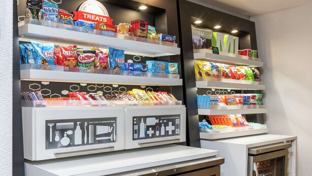 Eine Auswahl an Snacks mit verpackten Lebensmitteln und ein Kühlschrank mit Getränken.