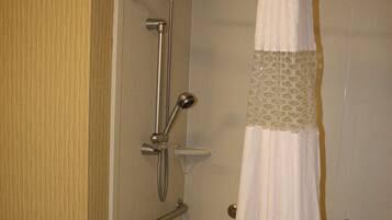A shower area with a glass door, a towel rack, and a showerhead.