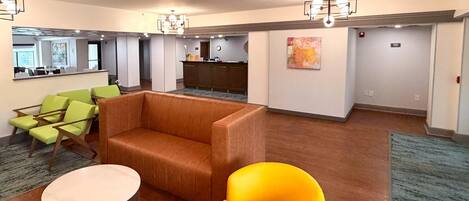 A spacious lobby with a reception desk, seating area, and a large window.
