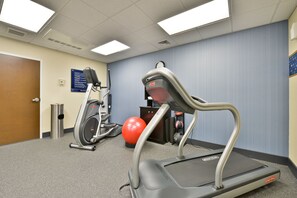 Un gimnasio con cintas de correr, elípticas y pelotas de ejercicio.