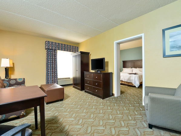 Une chambre d’hôtel avec un lit, un téléviseur posé sur une commode, un bureau et une chaise.