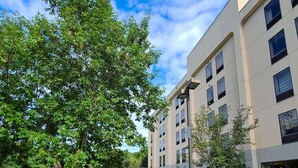 Un edificio moderno con múltiples ventanas y un patio con una mesa de picnic y bancos.