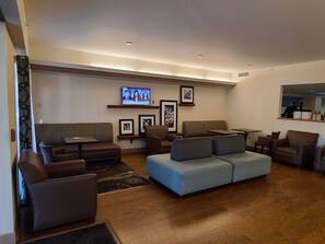 A modern living room with a sectional sofa, armchairs, a coffee table, and a flat-screen TV mounted on the wall. - Comfort Inn Saco-Old Orchard Beach (Saco)