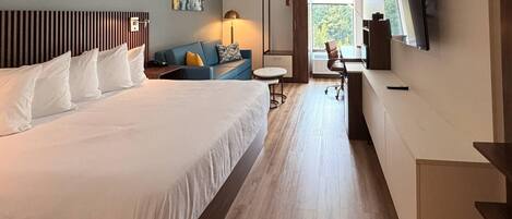 Habitación de hotel con una cama grande, un sofá, un escritorio y un televisor.