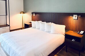 A hotel room with a large bed, a bedside table, a lamp, and a wall-mounted phone. - Comfort Inn Saco-Old Orchard Beach (Saco)