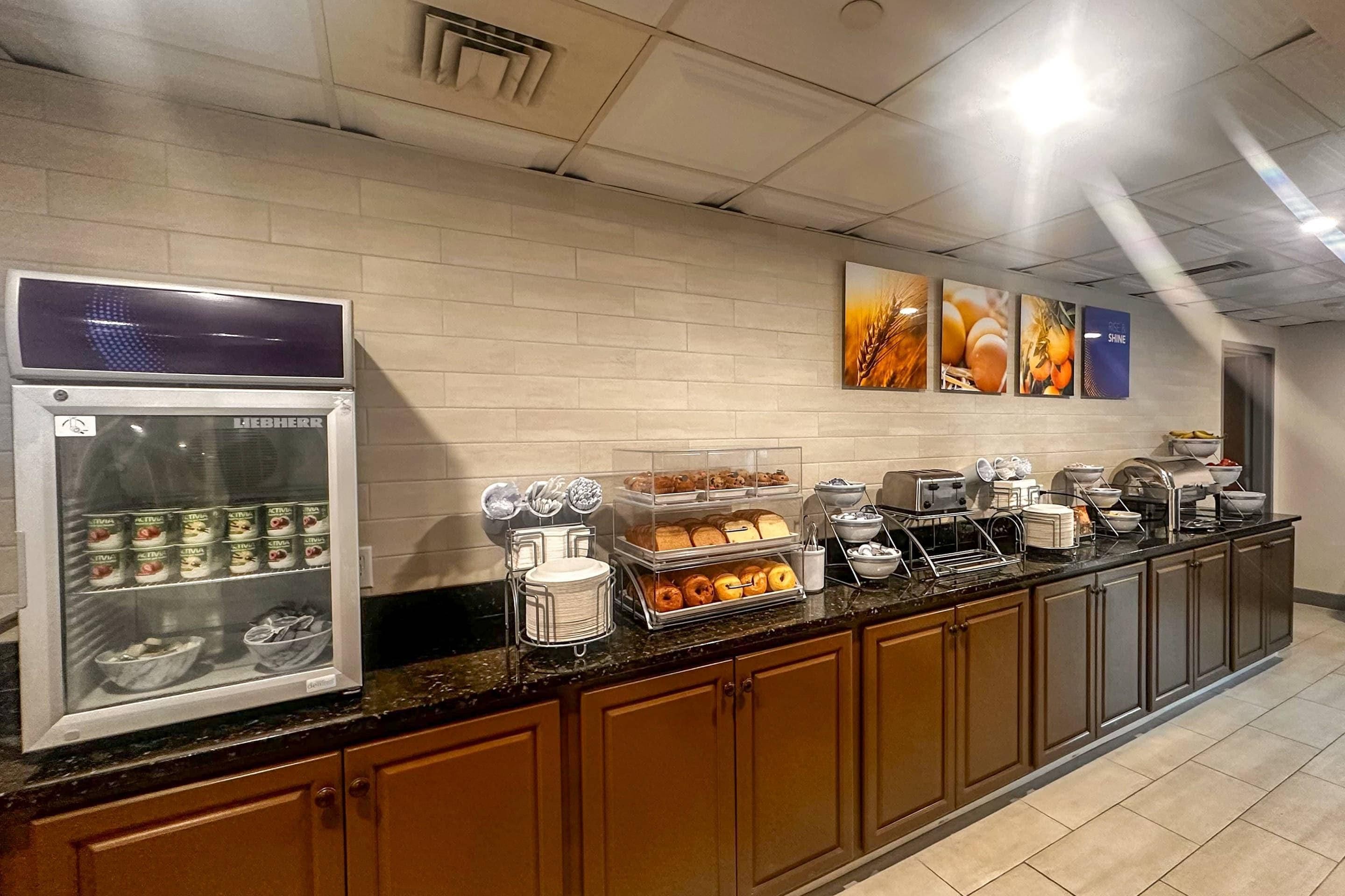 A self-service breakfast area with a refrigerator, hot food station, and various food items.