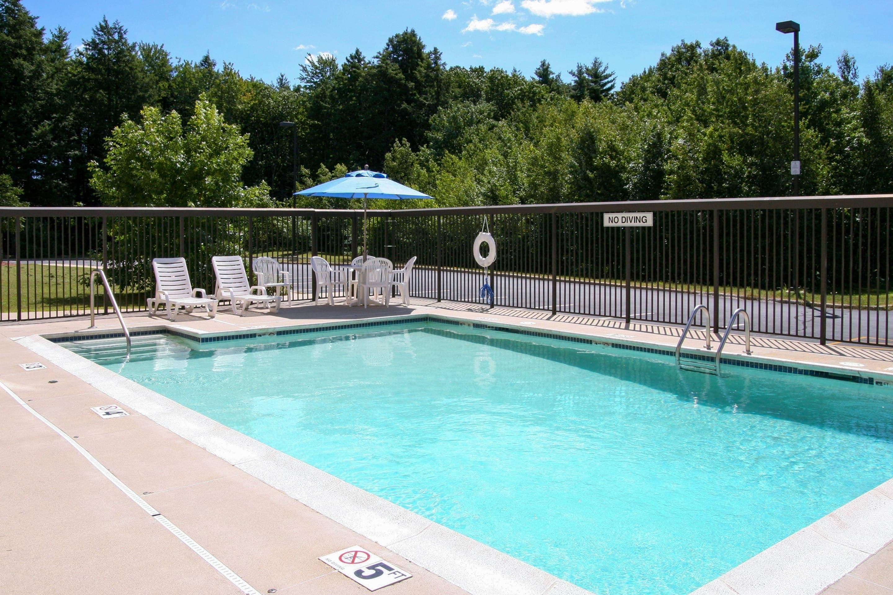 A swimming pool with lounge chairs and a no diving sign.