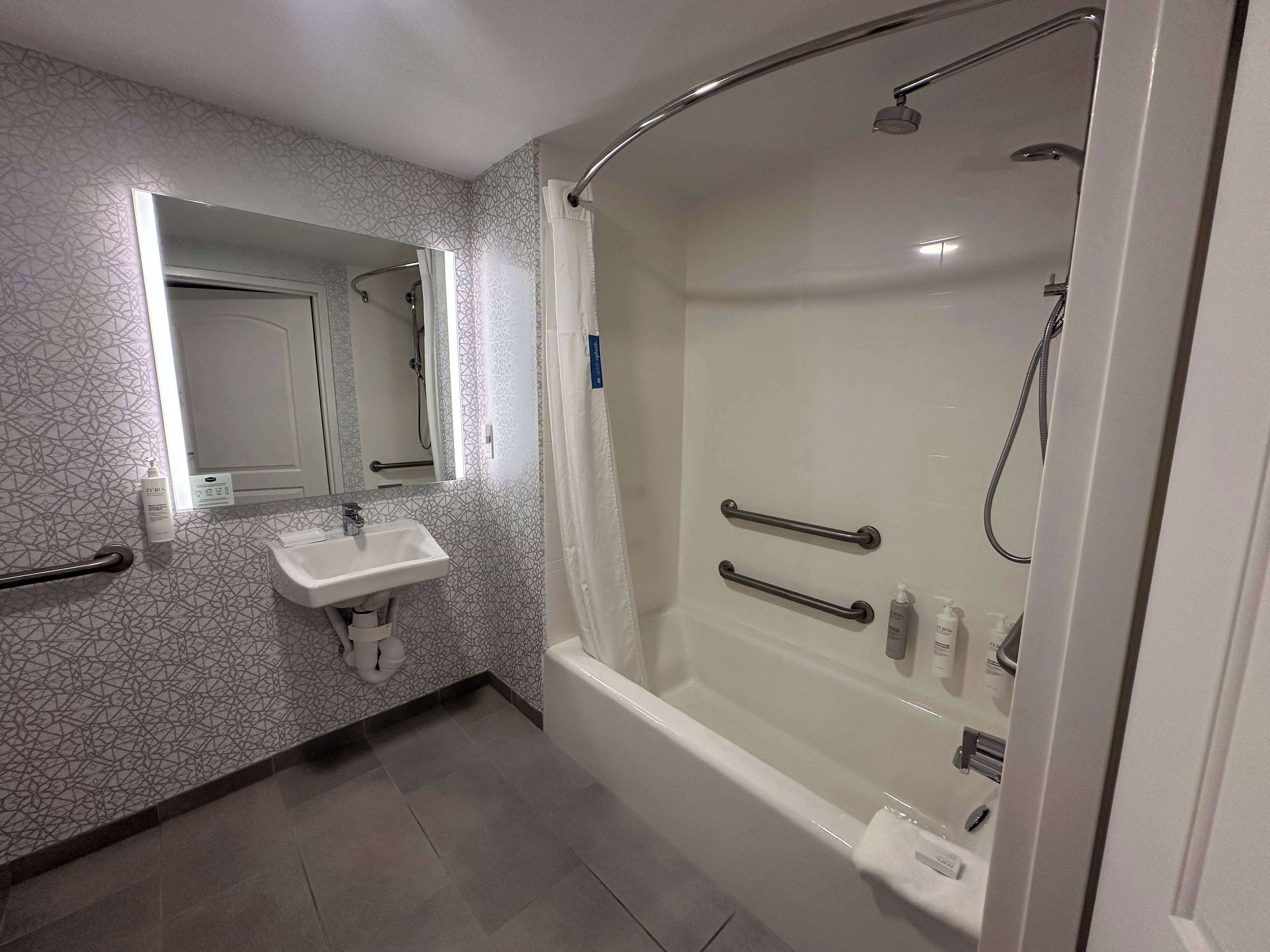 A modern bathroom with a shower, a sink, and a toilet.