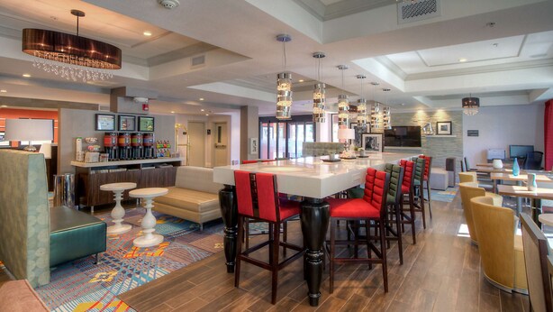 A spacious hotel lobby with a central bar area, multiple seating options, and a patterned carpet.