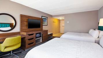 A hotel room with a bed, a desk with a chair, a television, and a mirror.