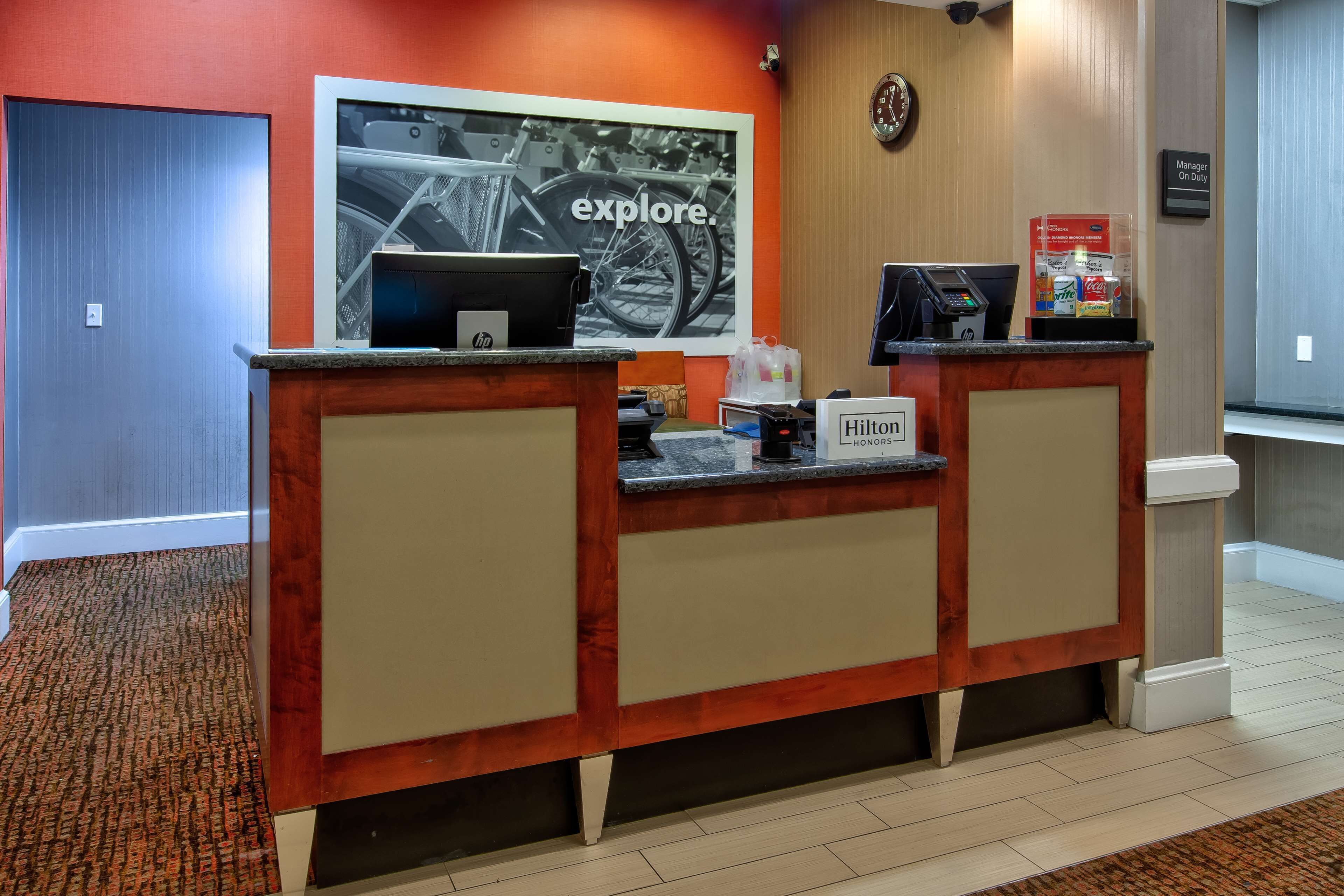 A hotel reception desk with a computer, a phone, and a sign that reads "Manager On Duty".