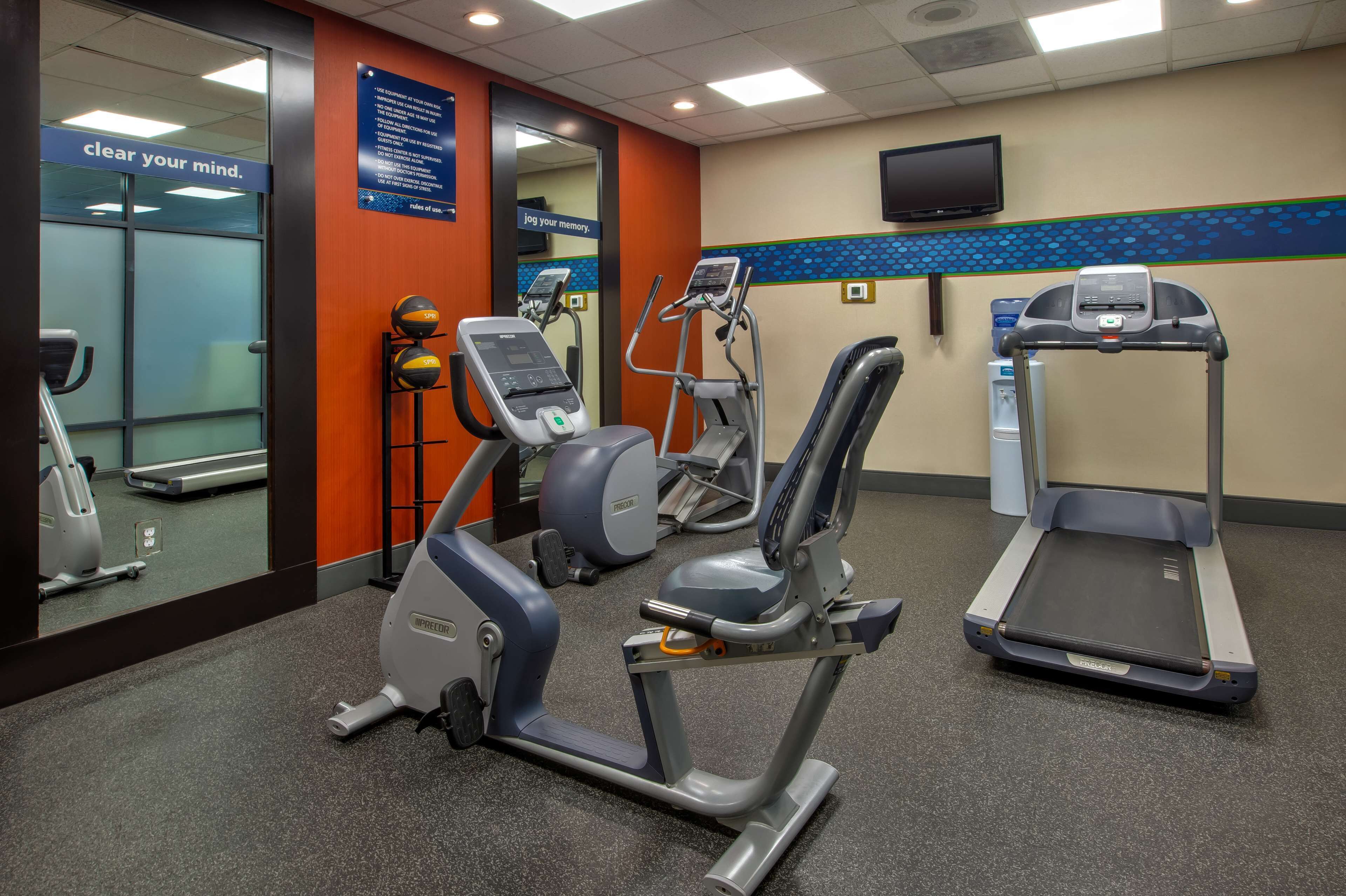 A fitness center with cardio machines, a water dispenser, and motivational posters.