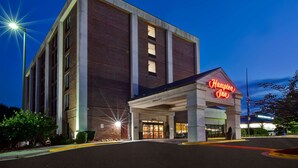A Hampton Inn hotel with a brick facade, a neon sign, and a well-lit entrance. - Hampton Inn College Park (College Park)