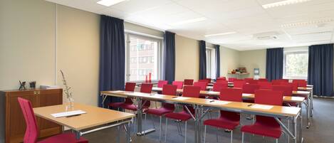 A classroom with rows of desks and chairs, a podium, and large windows with curtains.
