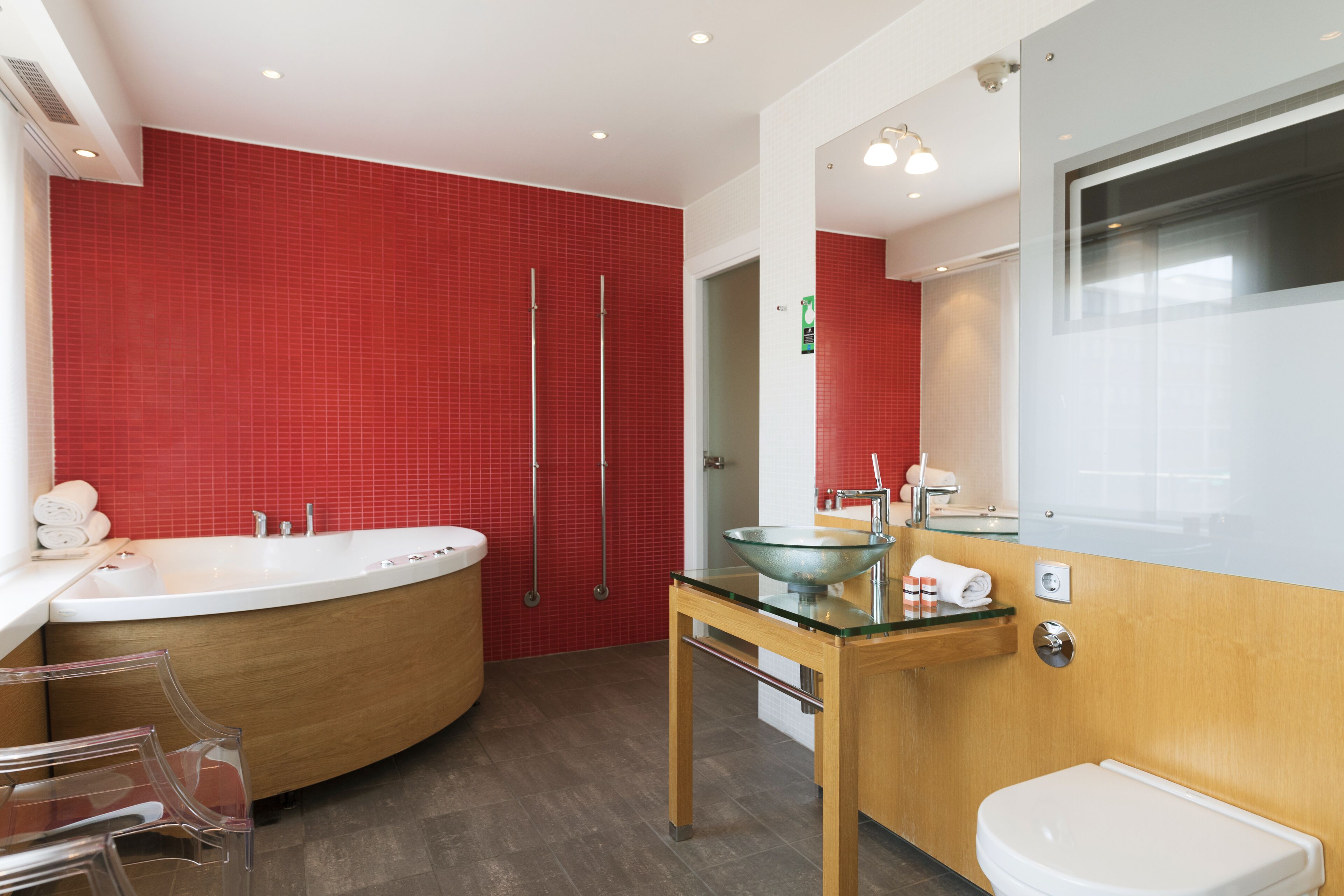 A modern bathroom with a bathtub, a glass sink, and a toilet.