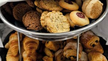 Una bandeja de tres niveles con una variedad de productos horneados, como galletas, muffins y cruasanes.