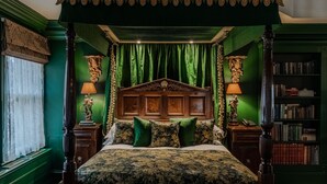 A four-poster canopy bed with green drapes, a wooden headboard, and matching green pillows. - The Rookery Hotel (London)