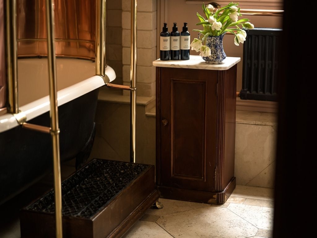 Ein Badezimmer mit Holzschrank, Marmorplatte und einer Vase mit Blumen.