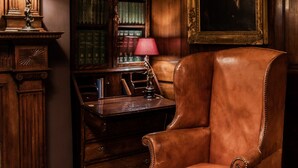 A study room with a leather armchair, wooden bookshelves, a desk, and a framed portrait. - The Rookery Hotel (London)