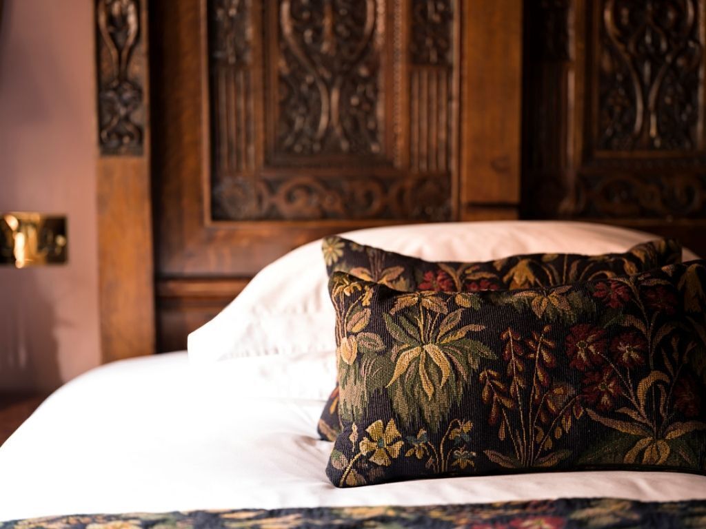 Una cama con un cojín estampado y un cabecero de madera.
