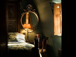 A bedroom with a bed, a mirror, a lamp, a chair, and a wooden cabinet. - The Rookery Hotel (London)