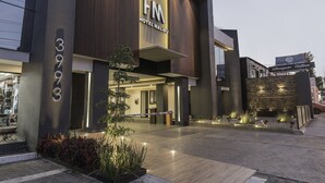 A modern hotel with a prominent 'HM' sign, a well-lit entrance, and a paved driveway. - Hotel Malibu (Zapopan)