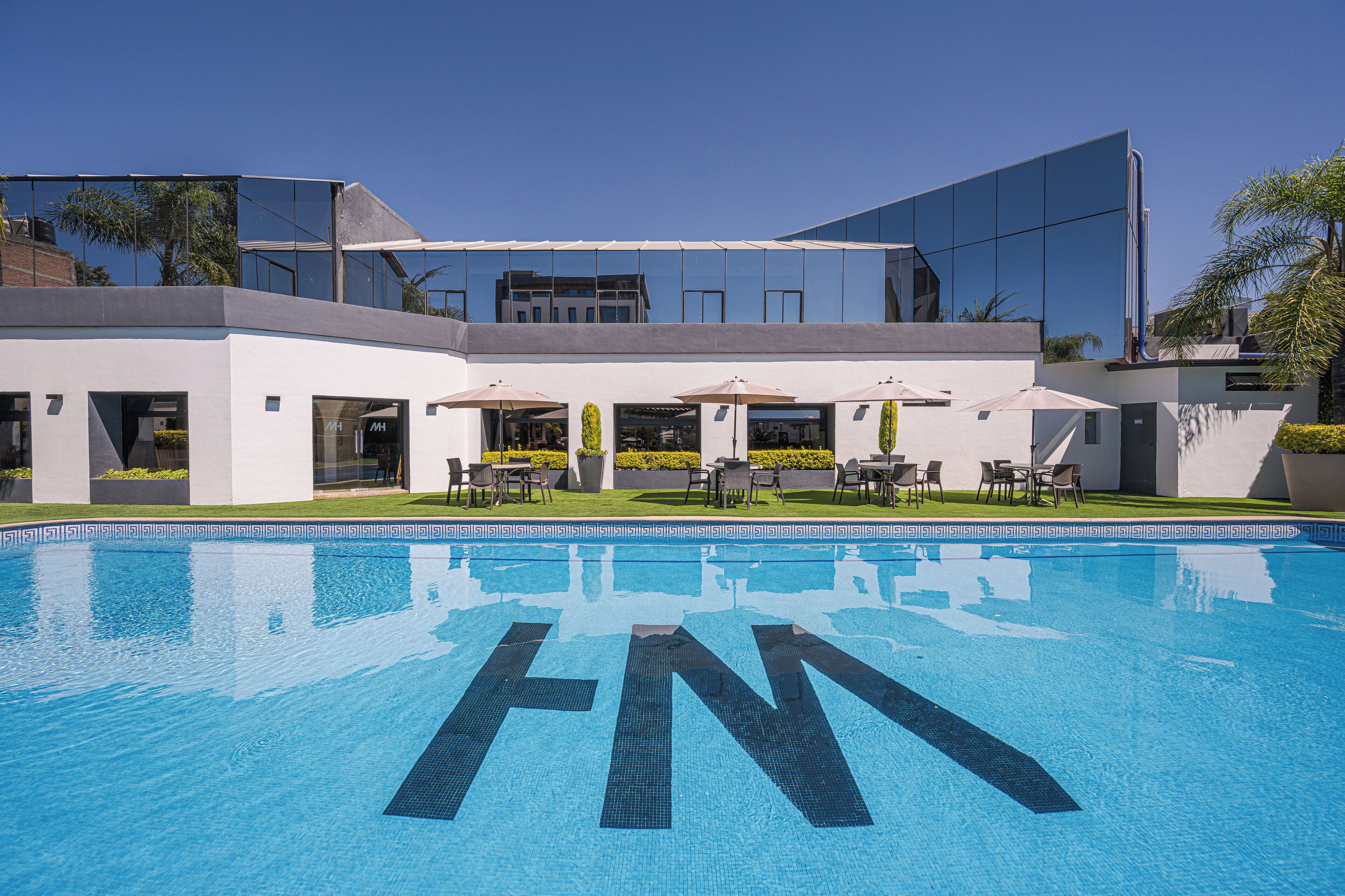 Un hôtel moderne doté d’une piscine, d’un espace extérieur aménagé et offrant une vue dégagée sur les environs.