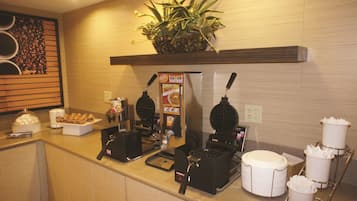 Un coin petit-déjeuner équipé d’une machine à gaufres, d’une machine à café et agrémenté d’une plante fixée au mur.