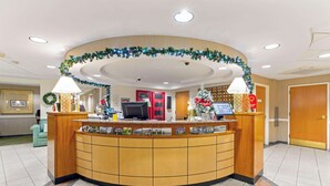 A reception area with a curved wooden desk, a computer, and a Christmas tree. - La Quinta Inn & Suites by Wyndham Boston Somerville (Somerville)