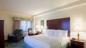 A hotel room with a large bed, a desk, a chair, and two bedside lamps. - La Quinta Inn & Suites by Wyndham Boston Somerville (Somerville)