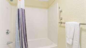 A bathroom with a white bathtub, a shower curtain, and a towel rack.