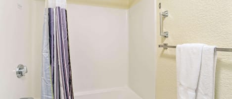 A bathroom with a white bathtub, a shower curtain, and a towel rack.