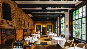 A restaurant with brick walls, white tables, and candle-lit tables. - The Dylan Amsterdam (Amsterdam)